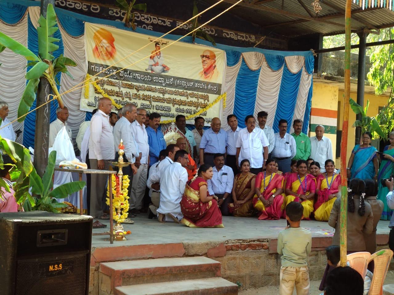 Guests and teachers on a decorated stage with a banner and a ceremonial lamp