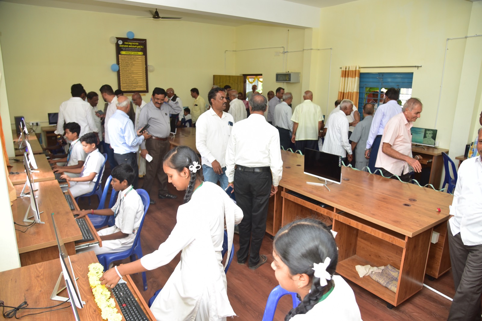 Students working at the new computers as trustees and guests look on