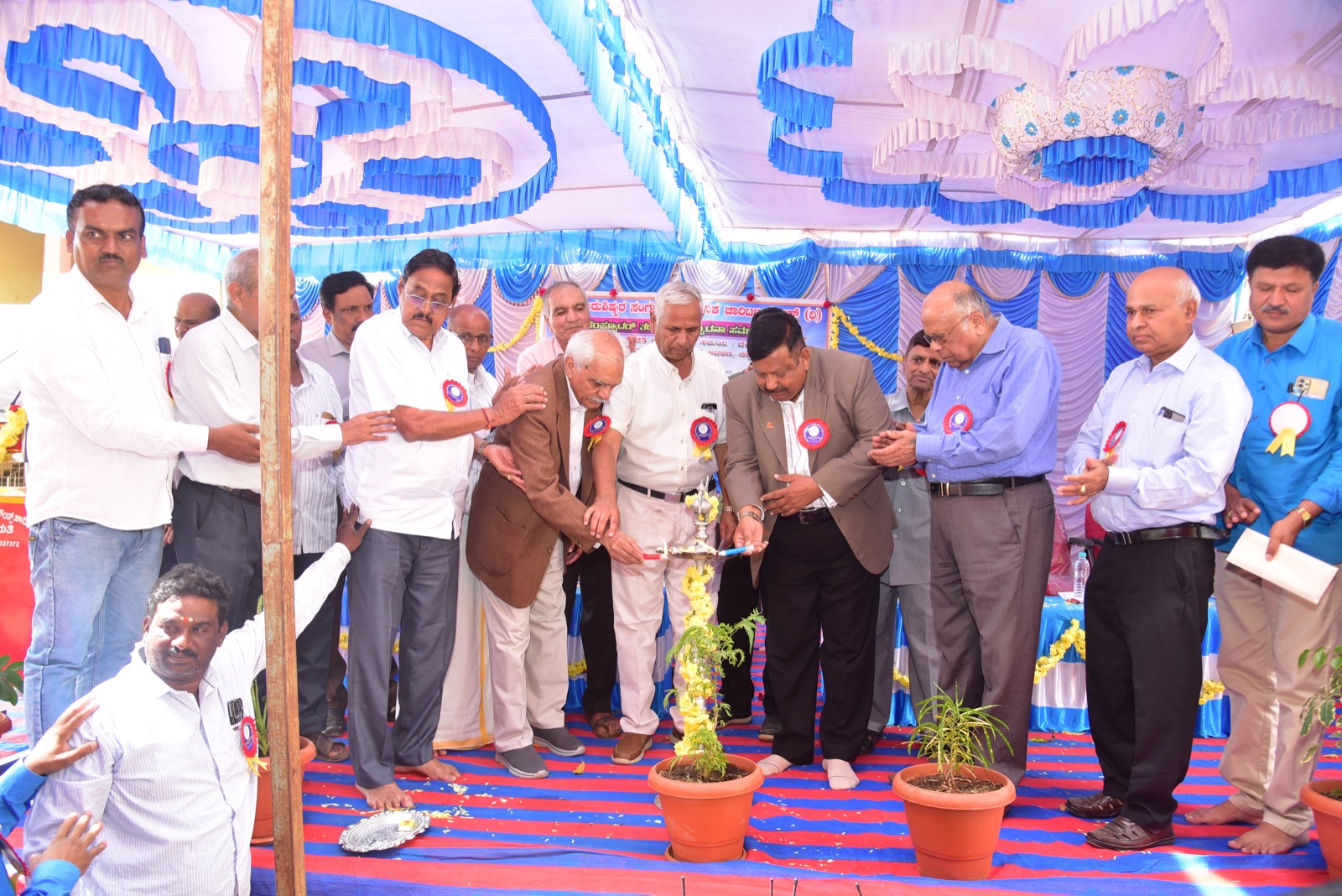 Trustees and guests lighting the ceremonial lamp on a decorated stage