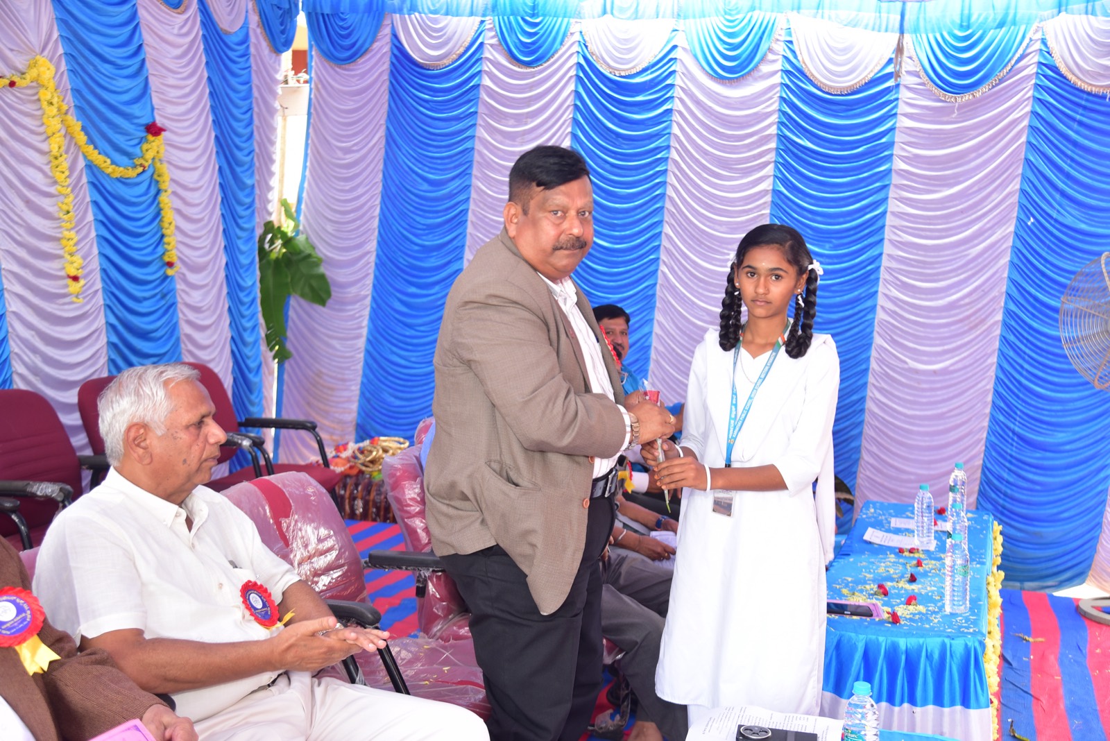 A student in school uniform welcoming a guest on stage